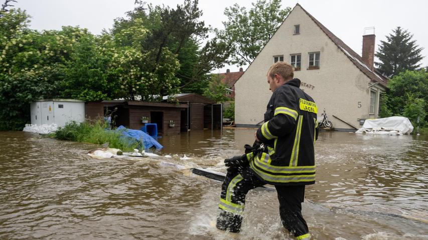 02.06.2024, Bayern, Wertingen: Ein Feuerwehrmann geht über eine überflutete Straße in Wertingen. Nach dem Starkregen der letzten Tage kam es zu schweren Überschwemmungen in der Region.