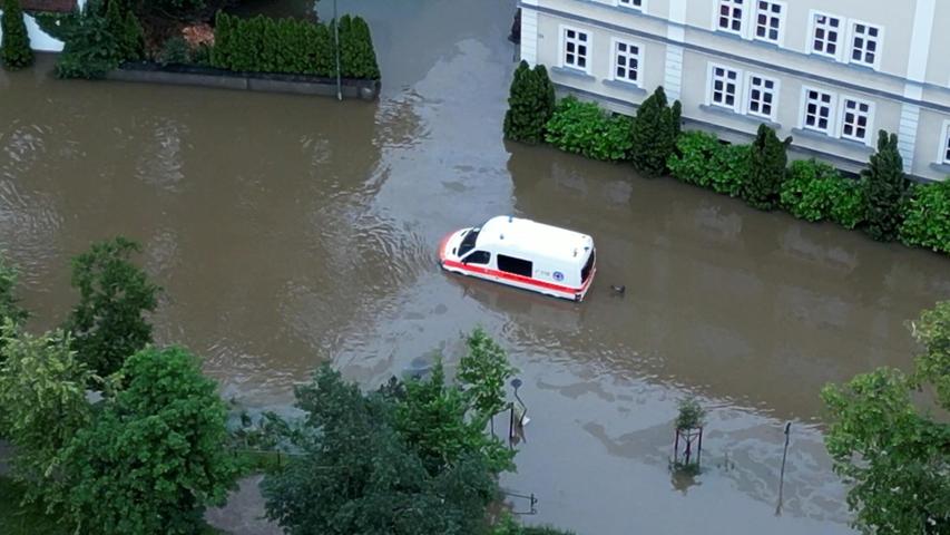 Ein Krankenwagen fährt über eine überschwemmte Straße in Schrobenhausen im Landkreis Neuburg-Schrobenhausen. Auch hier herrscht seit Samstag der Katastrophenfall.