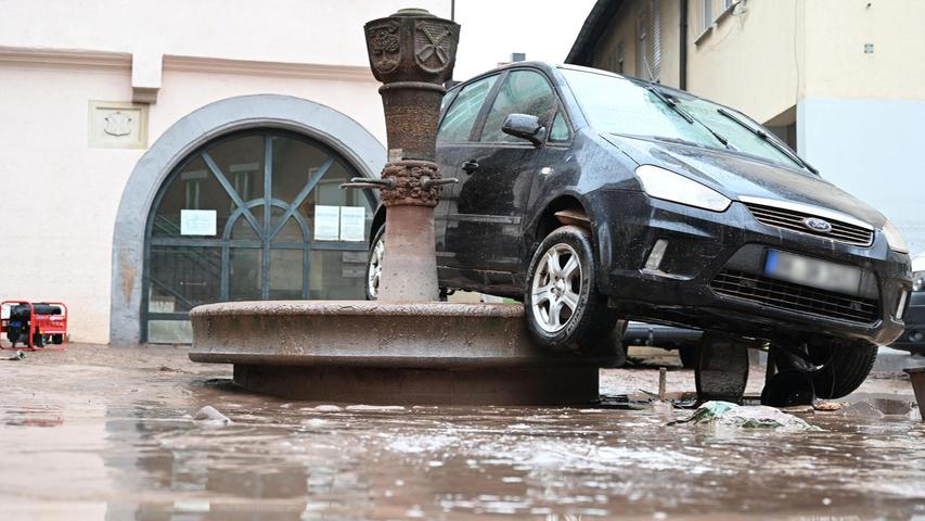Auf einem Brunnen in Rudersberg steht ein durch ein Hochwasser weggespültes Auto.