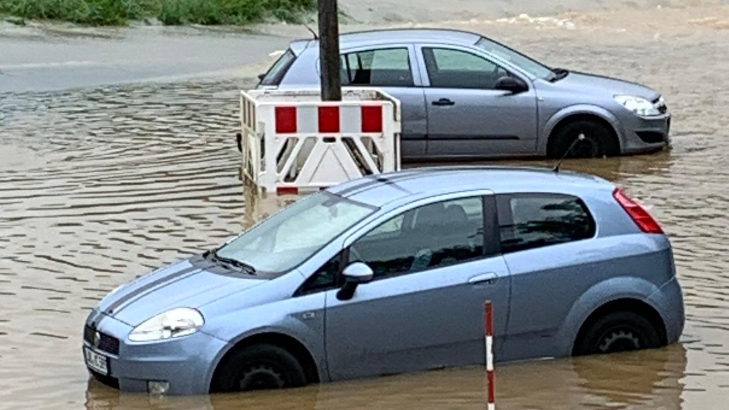 Offenbar auf dem Parkplatz vergessen worden: Ein Ford und ein Fiat stehen am Sonntagmorgen im Hochwasser bei Burgthann.