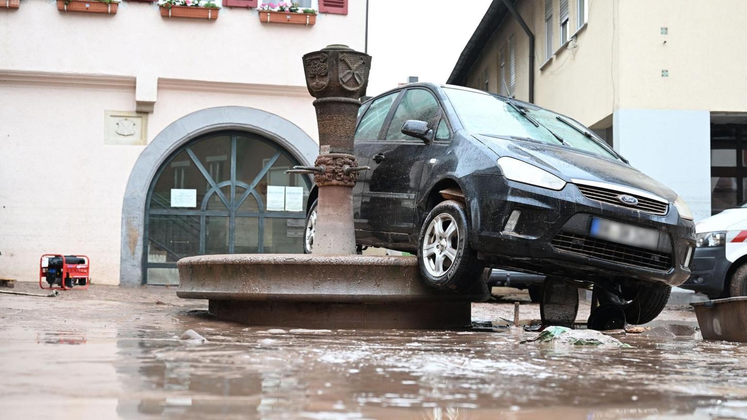 Auf einem Brunnen in Rudersberg hängt ein durch das Hochwasser weggespültes Auto.
