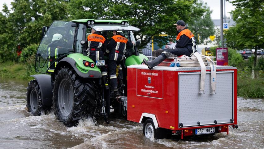 Feuerwehrleute fahren in Reichertshofen über eine überflutete Straße.