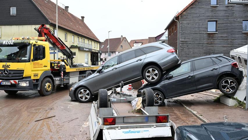 Auf einer Straße in Miedelsbach im Rems-Murr-Kreis (Baden-Württemnerg) stehen Fahrzeuge, die vom Hochwasser weggespült wurden.