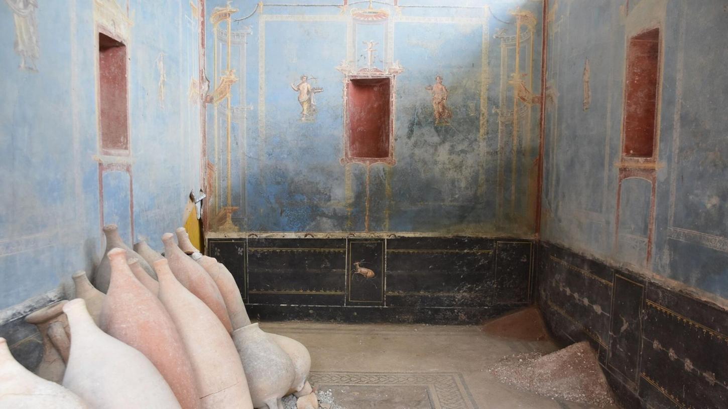 Ein Raum mit blauen Wänden und gemalten weiblichen Figuren ist in Pompeji freigelegt worden.