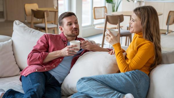 Cheerful relaxed couple sitting on sofa, chatting,