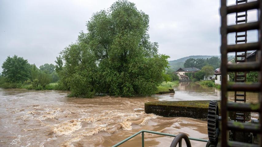 Wassermassen rauschen am Sonntag (2.6.2024) durch das Wehr der Mühle Gleusdorf (Landkreis Haßberge, Unterfranken). Im Itzgrund herrscht Hochwasser. Der Pegel Schenkenau hat die Meldestufe 3 erreicht. Straßen sind überschwemmt, das Überflutungsgebiet reicht an die ersten Häuser heran.