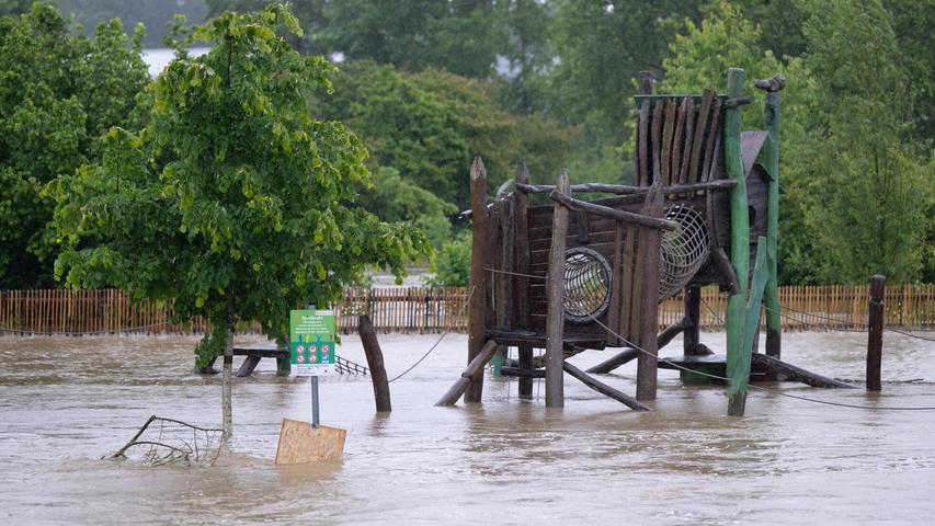 Bayern, Aichach: Eine Wiese mit einem Spielplatz ist im Ortskern überflutet.