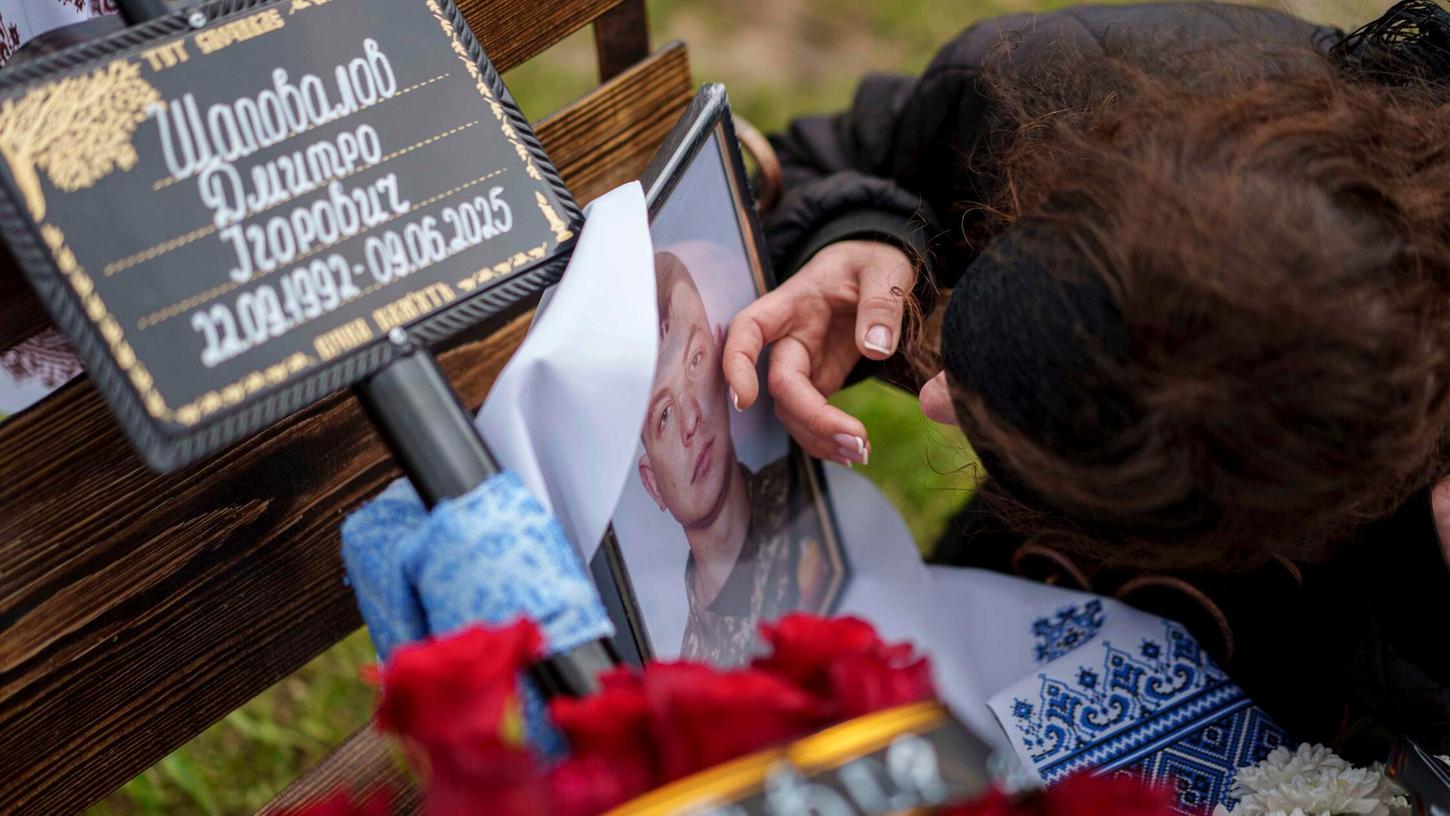 13.06.2025, Ukraine, Jossypiwka: Olena streichelt ein Foto ihres Mannes, Soldat Dmytro Schapowalow, während seiner Beerdigungsfeier im Dorf Jossypiwka, Region Winnyzja, Ukraine. 13.06.2025, Ukraine, Jossypiwka: Olena streichelt ein Foto ihres Mannes, Soldat Dmytro Schapowalow, während seiner Beerdigungsfeier im Dorf Jossypiwka, Region Winnyzja, Ukraine.