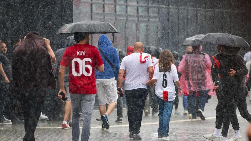 Das haben sie sich sicherlich anders vorgestellt: Fussballfans in Dortmund laufen im strömenden Regen zum Stadion.