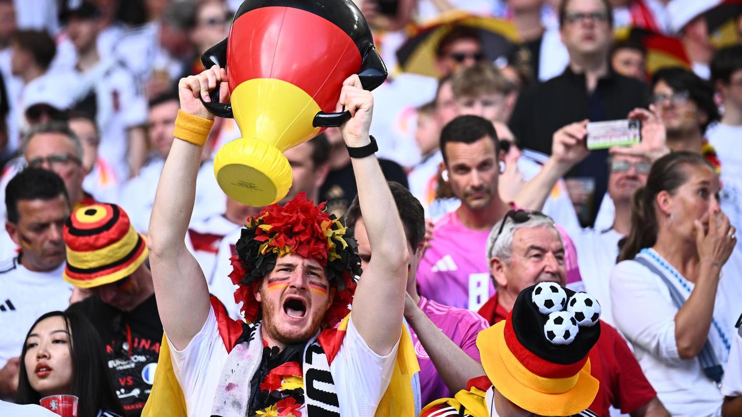 Ein Fan von Deutschland feiert auf der Tribüne mit einer aufblasbaren Trophäe.