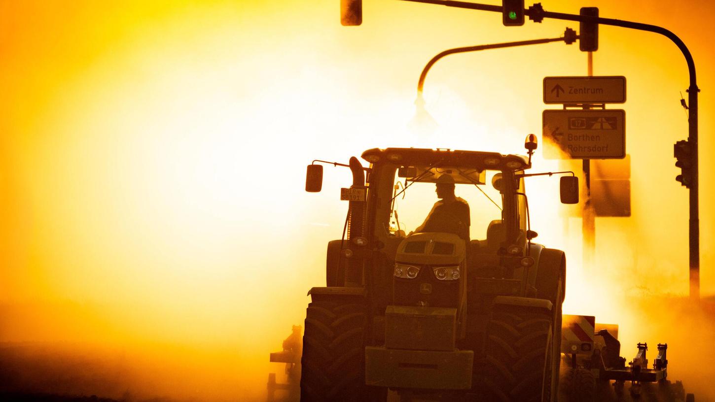 Ein Traktor pflügt in einer Staubwolke vor den Strahlen der untergehenden Sonne ein Feld: Am Samstag wird es richtig heiß. Ein Traktor pflügt in einer Staubwolke vor den Strahlen der untergehenden Sonne ein Feld: Am Samstag wird es richtig heiß.