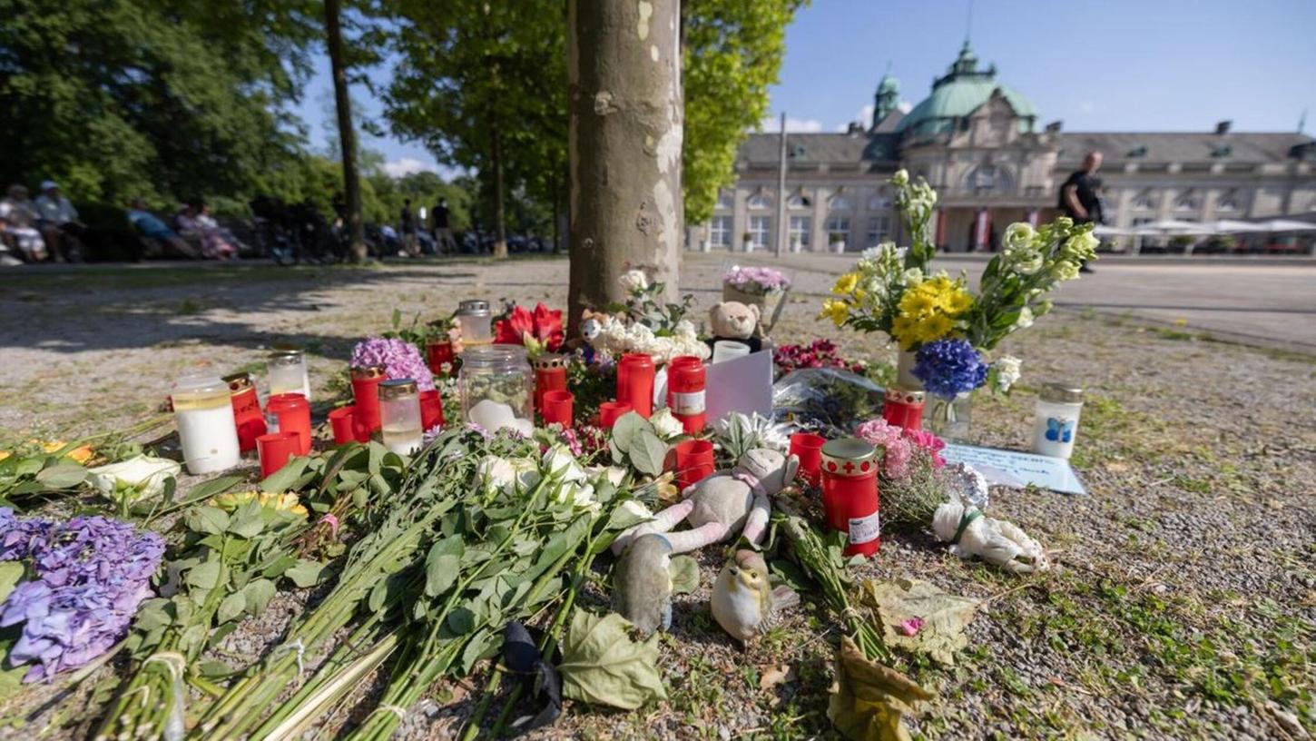 Blumen, Kerzen und handgeschriebene Trauerbekundungen an einem Baum im Kurpark Bad Oeynhausen.