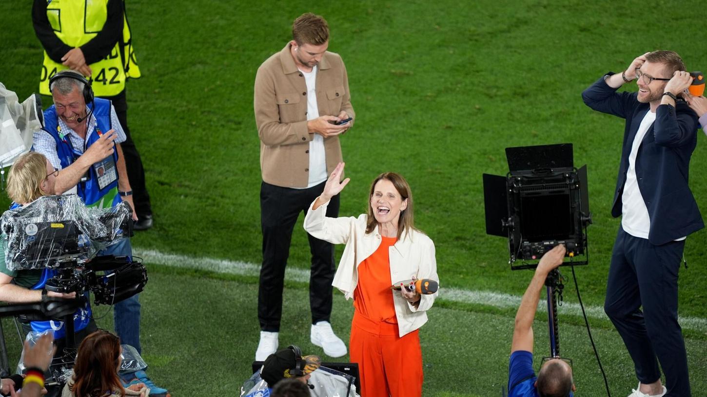 Die deutschen Fans sorgten für eine gute Stimmung bei der Berichterstattung um ZDF-Moderatorin Katrin Müller-Hohenstein (M) nach dem Spiel.