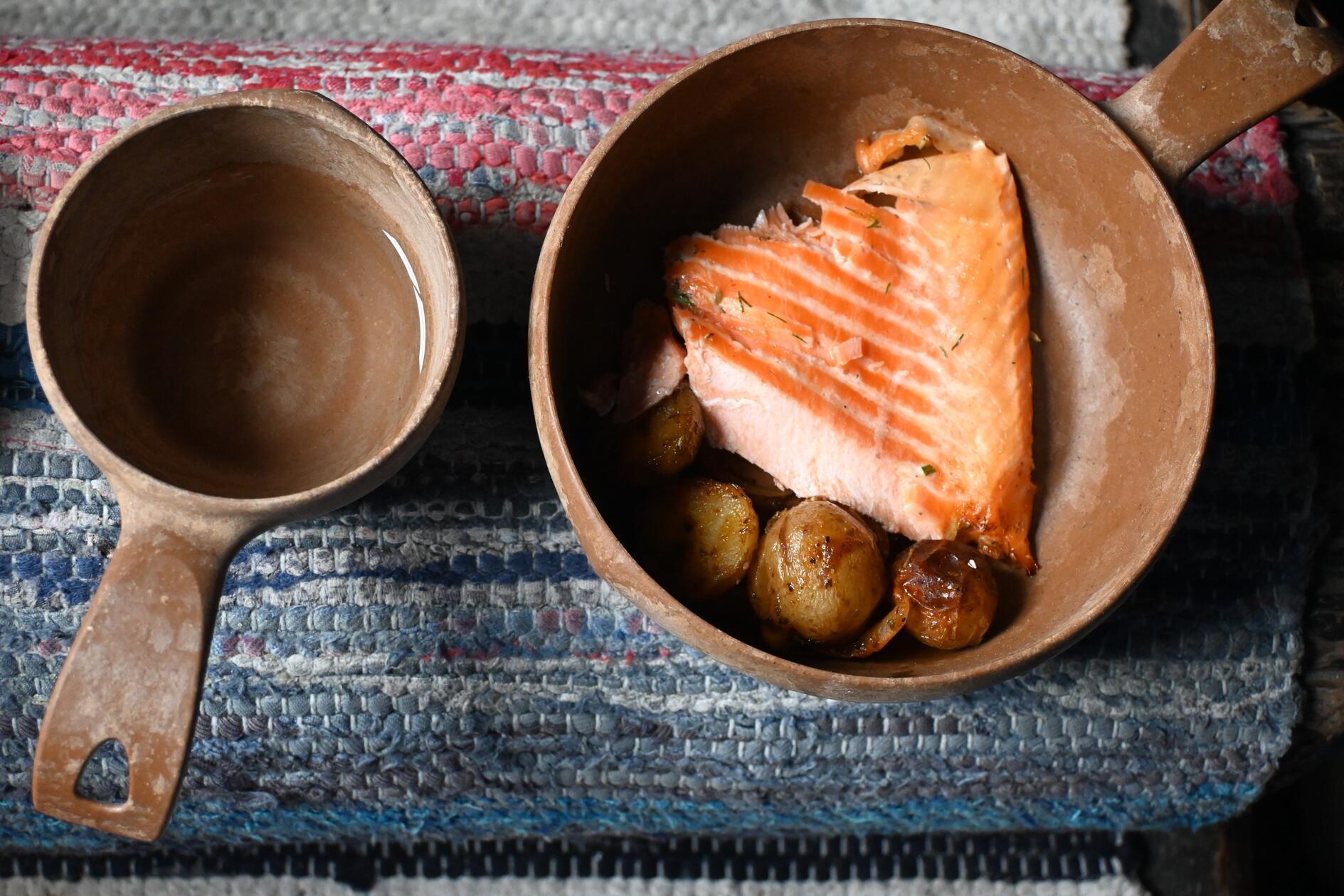 Frisch gefangen! Der Flammlachs landet direkt von der Feuerstelle in der traditionellen Holzschale. Auch die Kåsa, die Holztasse, darf nicht fehlen. Vor allem Weißfisch fangen sie hier, pro Saison und pro Fang-Brücke kommen schon 5000 Kilo pro Jahr zusammen.