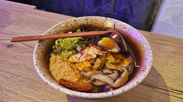 "Spicy Chicken"-Ramen in Hühnerbrühe mit Nudeln, gehacktem Maishuhn, Morcheln, getrockneten Tomaten, Kimchi, Shitake-Pilzen, Chili-Fäden, Frühlingszwiebeln, weich gekochtem Ei und Chili-Öl.
