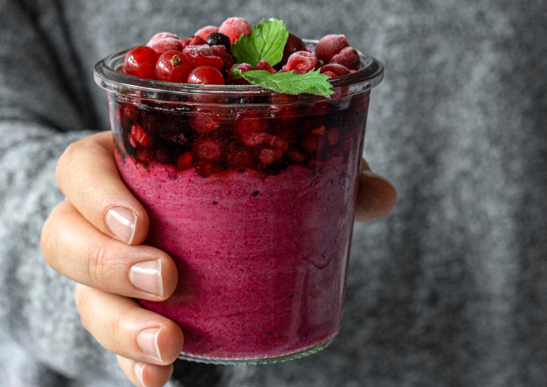 close-up-hand-holding-fruity-smoothie-glass
