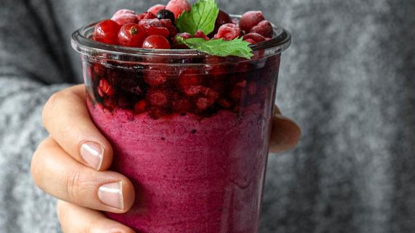 close-up-hand-holding-fruity-smoothie-glass
