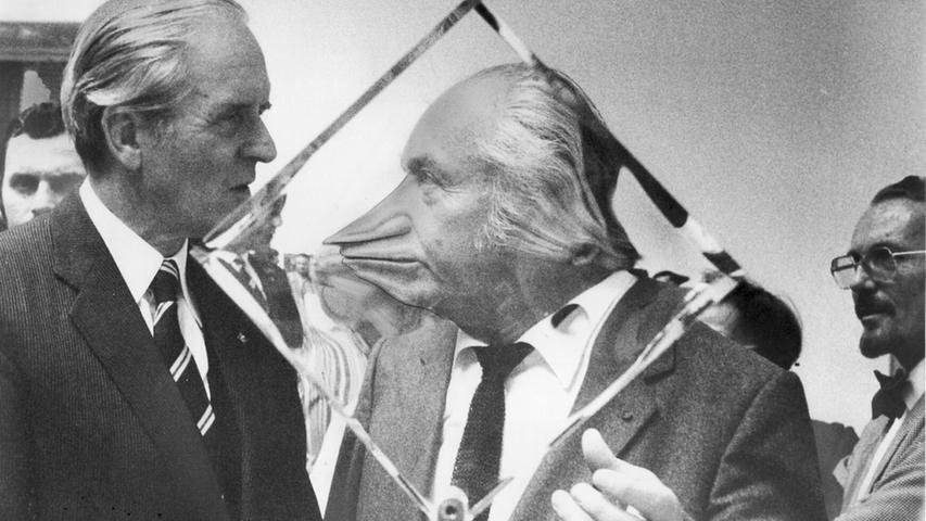 Dass Museumsdirektoren als surreale Kunstwerke fungieren können, bewies im September 1981 im Rahmen der 29. Jahresausstellung des Deutschen Künstlerbundes in Nürnberg humorvoll der damalige Direktor der Kunsthalle, Curt Heigl. Während er sich mit dem zur Eröffnung angereisten damaligen Bundespräsidenten Karl Carstens (links) unterhielt, stand er hinter einem spezialgeschliffenen gläsernen Ausstellungsobjekt des Künstlers Victor Bonato. Schon 1968 hatte der Deutsche Künstlerbund zuvor mit seiner Jahresausstellung einmal Nürnberg beehrt. Damals hatte Joseph Beuys für Irritation gesorgt, als er im Künstlerhaus die Installationen „Fettecke“ und „Luftpumpen mit Fett“ zeigte. Bei der Ausstellung im Jahr 1981 ging es deutlich fettärmer zu. Dass Museumsdirektoren als surreale Kunstwerke fungieren können, bewies im September 1981 im Rahmen der 29. Jahresausstellung des Deutschen Künstlerbundes in Nürnberg humorvoll der damalige Direktor der Kunsthalle, Curt Heigl. Während er sich mit dem zur Eröffnung angereisten damaligen Bundespräsidenten Karl Carstens (links) unterhielt, stand er hinter einem spezialgeschliffenen gläsernen Ausstellungsobjekt des Künstlers Victor Bonato. Schon 1968 hatte der Deutsche Künstlerbund zuvor mit seiner Jahresausstellung einmal Nürnberg beehrt. Damals hatte Joseph Beuys für Irritation gesorgt, als er im Künstlerhaus die Installationen „Fettecke“ und „Luftpumpen mit Fett“ zeigte. Bei der Ausstellung im Jahr 1981 ging es deutlich fettärmer zu.