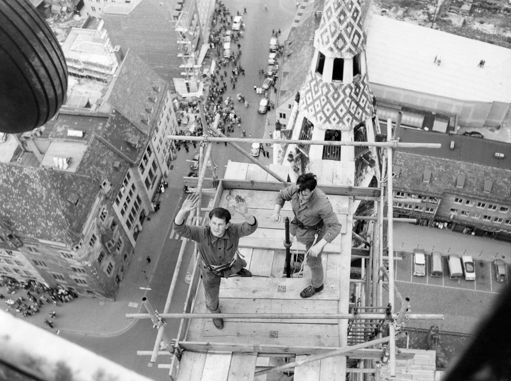 "Erregende Minuten über St. Lorenz": diese Aufnahme der eingerüsteten Turmspitze gelang unserer Fotografin Gertrud Gerardi im Mai 1959 durch die geöffnete Tür eines Helikopters der US-Armee. Er war vom Hans-Sachs-Platz gestartet, um die goldene Turmzierde, einen Stern mit Engel, zur Spitze des 81 Meter hohen Südturms der Lorenzkirche zu befördern, wo sie sodann montiert wurde und sich heute noch dreht. Der Einsatz des damals noch ungewöhnlichen Fluggeräts zog zahlreiche Nürnberger auf die Straßen der Altstadt, von wo sie das zehnminütige, aufregende Ringen von Besatzung und Handwerkern gegen den starken Wind beobachteten.