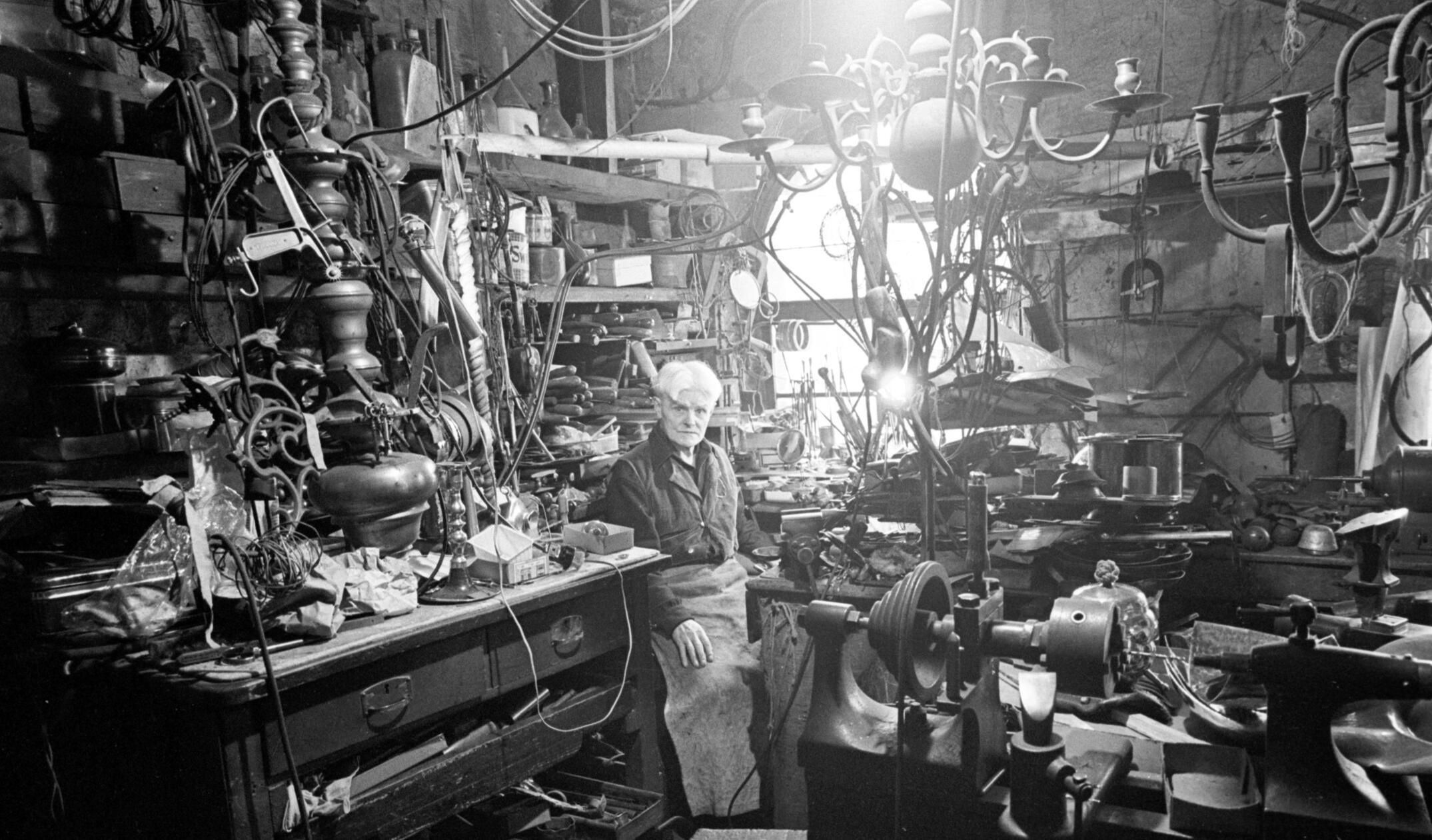 „Georg Birklein in seinem Gehäuse: Er sitzt inmitten einer verwirrenden Fülle von Werkzeug und Gerät“, so wurde dieses Bild im Herbst 1966 in den NN umschrieben. In der Unteren Kreuzgasse 4 befand sich die Werkstatt des Silberschmieds, der bei einem Besteckmacher ausgebildet worden war. Vom Fernweh gepackt heuerte er als junger Mann auf Schiffen der Deutschen Lloyd an, kam so bis nach Südamerika und Australien. Nach vielen Jahren auf hoher See kehrte er zurück nach Nürnberg, und zu seinem Handwerk. Das Gold- und Silberschmiedehandwerk wurde übrigens 2025 ins Verzeichnis des immateriellen Kulturerbes der UNESCO aufgenommen.