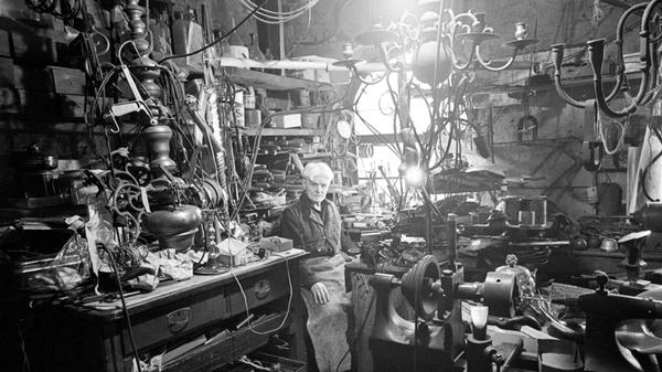 „Georg Birklein in seinem Gehäuse: Er sitzt inmitten einer verwirrenden Fülle von Werkzeug und Gerät“, so wurde dieses Bild im Herbst 1966 in den NN umschrieben. In der Unteren Kreuzgasse 4 befand sich die Werkstatt des Silberschmieds, der bei einem Besteckmacher ausgebildet worden war. Vom Fernweh gepackt heuerte er als junger Mann auf Schiffen der Deutschen Lloyd an, kam so bis nach Südamerika und Australien. Nach vielen Jahren auf hoher See kehrte er zurück nach Nürnberg, und zu seinem Handwerk. Das Gold- und Silberschmiedehandwerk wurde übrigens 2025 ins Verzeichnis des immateriellen Kulturerbes der UNESCO aufgenommen.