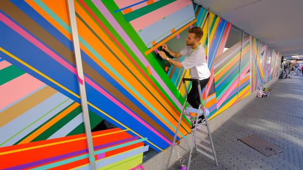 Die Schaufenster werden mit bunten Farben gestaltet, um das seit einem Jahr leerstehende Gebäude zu beleben - zumindest an der Fassade.