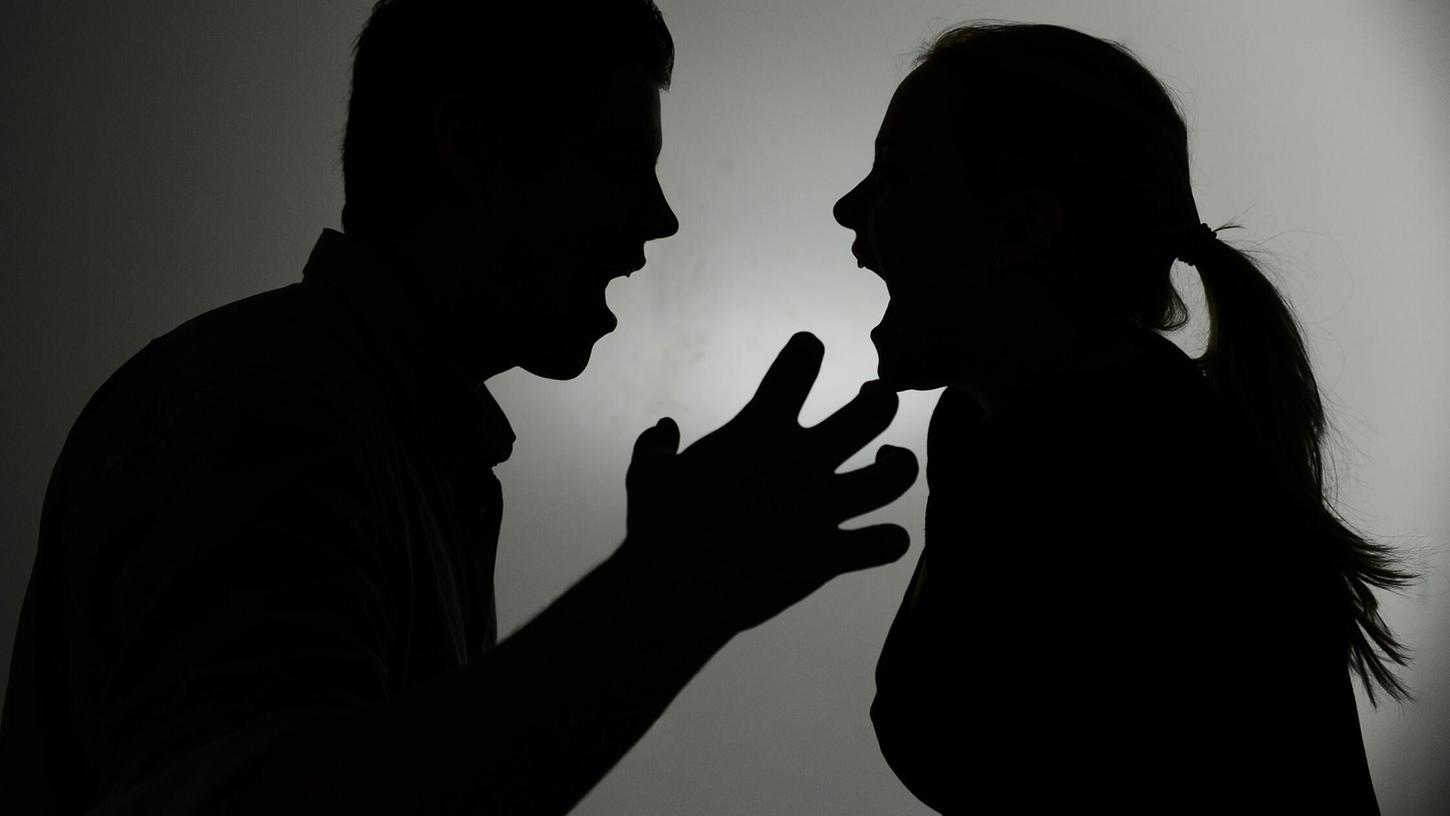 Ein als Silhouette abgebildeter Mann und eine Frau schreien sich an (Symbolbild). Ein als Silhouette abgebildeter Mann und eine Frau schreien sich an (Symbolbild).