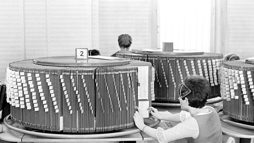 Wer bereits Mitte der 1960er Jahre glücklicher Besitzer eines Telefons war, und eine Telefonnummer benötigte, landete unter Umständen bei dieser hilfsbereiten Telefonistin an ihrem Arbeitsplatz im Fernmeldeamt 1 in der Karolinenstraße in Nürnberg. 8000 Anfragen gingen seinerzeit werktäglich bei der Telefonauskunft ein. In kürzester Zeit galt es – quasi im Handumdrehen – die gesuchte Telefonnummer in der sogenannten Drehauskunft zu finden, die die einzelnen Seiten des damaligen Amtlichen Fernsprechbuches enthielt. Um unvermeidliche Wartezeiten zu verkürzen, wurde deshalb 1967 auf Mikrofilmtechnik umgestellt. Wer bereits Mitte der 1960er Jahre glücklicher Besitzer eines Telefons war, und eine Telefonnummer benötigte, landete unter Umständen bei dieser hilfsbereiten Telefonistin an ihrem Arbeitsplatz im Fernmeldeamt 1 in der Karolinenstraße in Nürnberg. 8000 Anfragen gingen seinerzeit werktäglich bei der Telefonauskunft ein. In kürzester Zeit galt es – quasi im Handumdrehen – die gesuchte Telefonnummer in der sogenannten Drehauskunft zu finden, die die einzelnen Seiten des damaligen Amtlichen Fernsprechbuches enthielt. Um unvermeidliche Wartezeiten zu verkürzen, wurde deshalb 1967 auf Mikrofilmtechnik umgestellt.