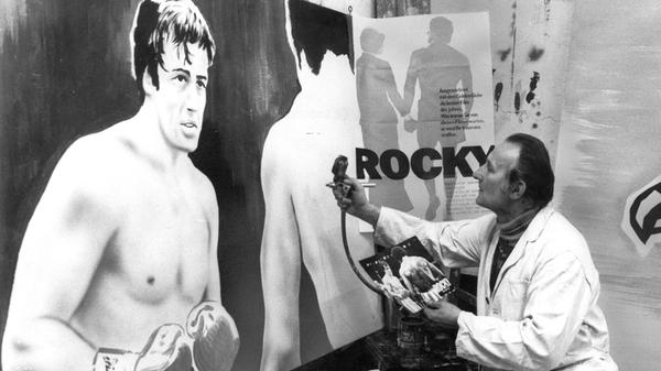 Mit geschultem Blick und einer Sprühpistole in der Hand erweckte Nürnbergs einziger und letzter Filmplakatmaler im Jahr 1977 eine überlebensgroße Boxkampfszene aus dem Film „Rocky“ auf einer Hartfaserplatte zum Leben. Jedes Werbeplakat, das der gelernte Kirchenmaler Herbert Koch in satten Farben gestaltete, war ein Unikat. Auf dem Höhepunkt des Kinobooms in den 50er und 60er Jahren war er für sage und schreibe dreißig Kinobetreiber im Nürnberger Raum künstlerisch tätig, Ende der 70er Jahre nur noch für drei: die Filmplakatmalerei wurde zur aussterbenden Kunst.