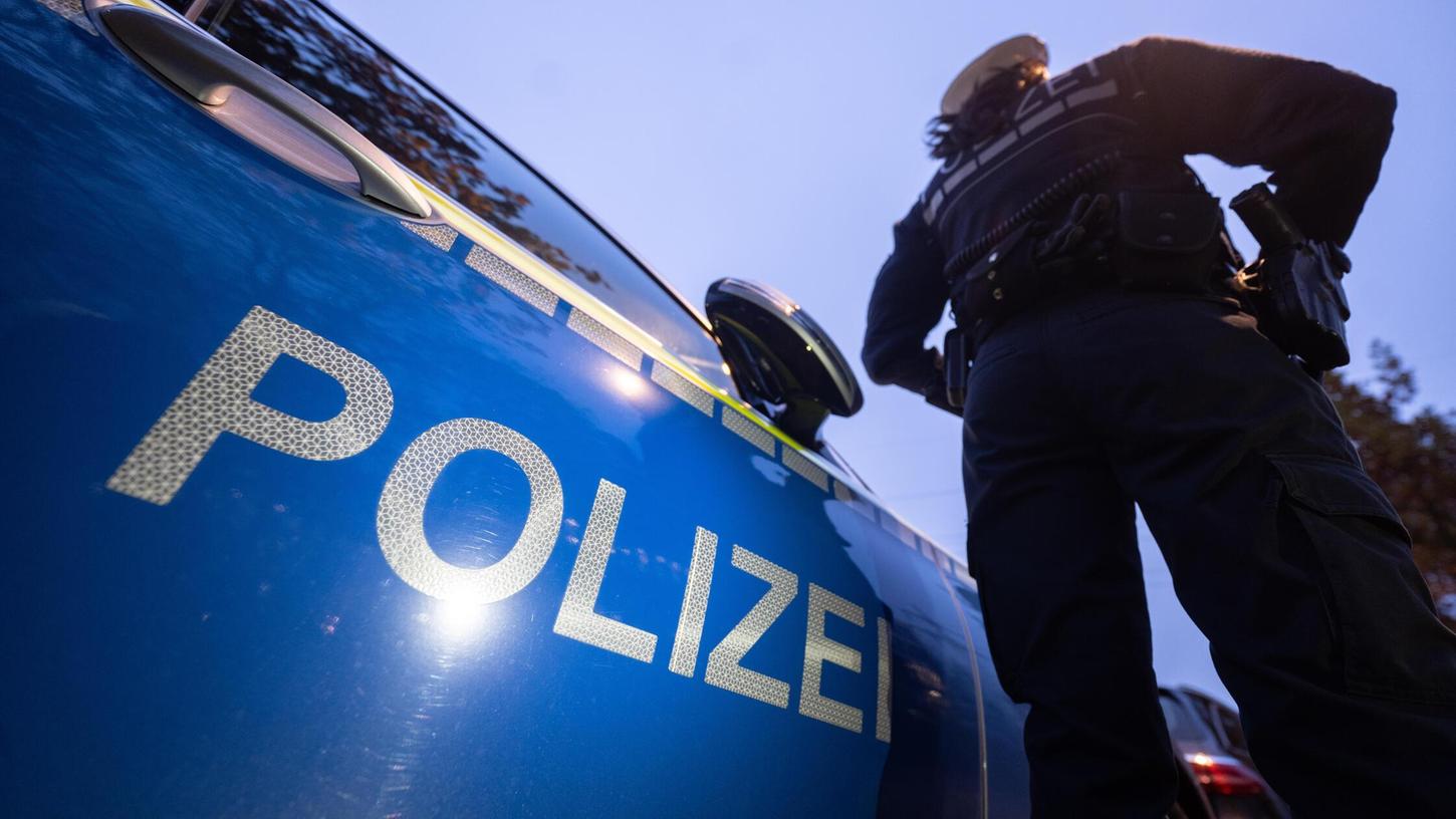 Eine Polizistin steht neben einem Polizeifahrzeug. Es handelt sich um ein Symbolbild. Eine Polizistin steht neben einem Polizeifahrzeug. Es handelt sich um ein Symbolbild.