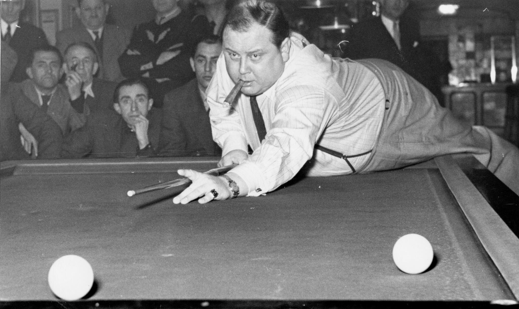 Zu Beginn der 1950er Jahre hatte Billard noch einen höheren sportlichen Stellenwert als heute. So richtete der 1. Billard-Club Nürnberg damals im Hotel Kaiserhof alljährlich Veranstaltungen aus, bei denen lokale und auch internationale Meister vor gespanntem Publikum gegeneinander antraten und ihr Können zeigten. Die Sportmode folgte dabei ihren eigenen Regeln, die Athleten erschienen klassisch-elegant. Im Eifer des Gefechtes war es aber wohl legitim, sich auch einmal des Sakkos zu entledigen. So wie es dieser Teilnehmer tat, der im Wettkampf vollen Körpereinsatz zeigte, jedoch auch eine gute Zigarre zu schätzen wusste.