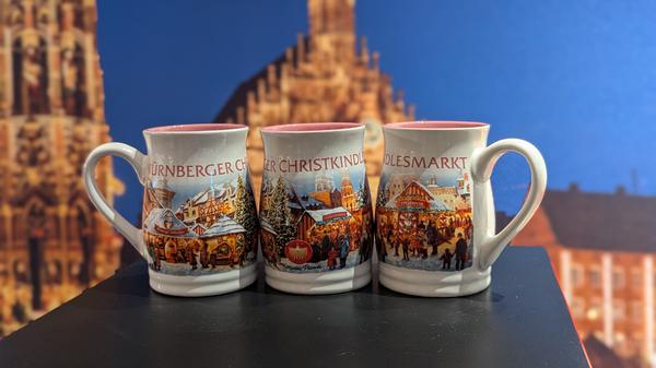 Auch 2024 bleibt das Design der Glühweintasse hell und bauchig. Verschiedene bauliche Wahrzeichen der Stadt Nürnberg sind auf der Tasse abgedruckt, außerdem Eindrücke vom Christkindlesmarkt. Der Schriftzug "Nürnberger Christkindlesmarkt" zeigt die Zugehörigkeit der Tasse, auch das Emblem des Nürnberger Christkindes ist auf der Tasse zu sehen.