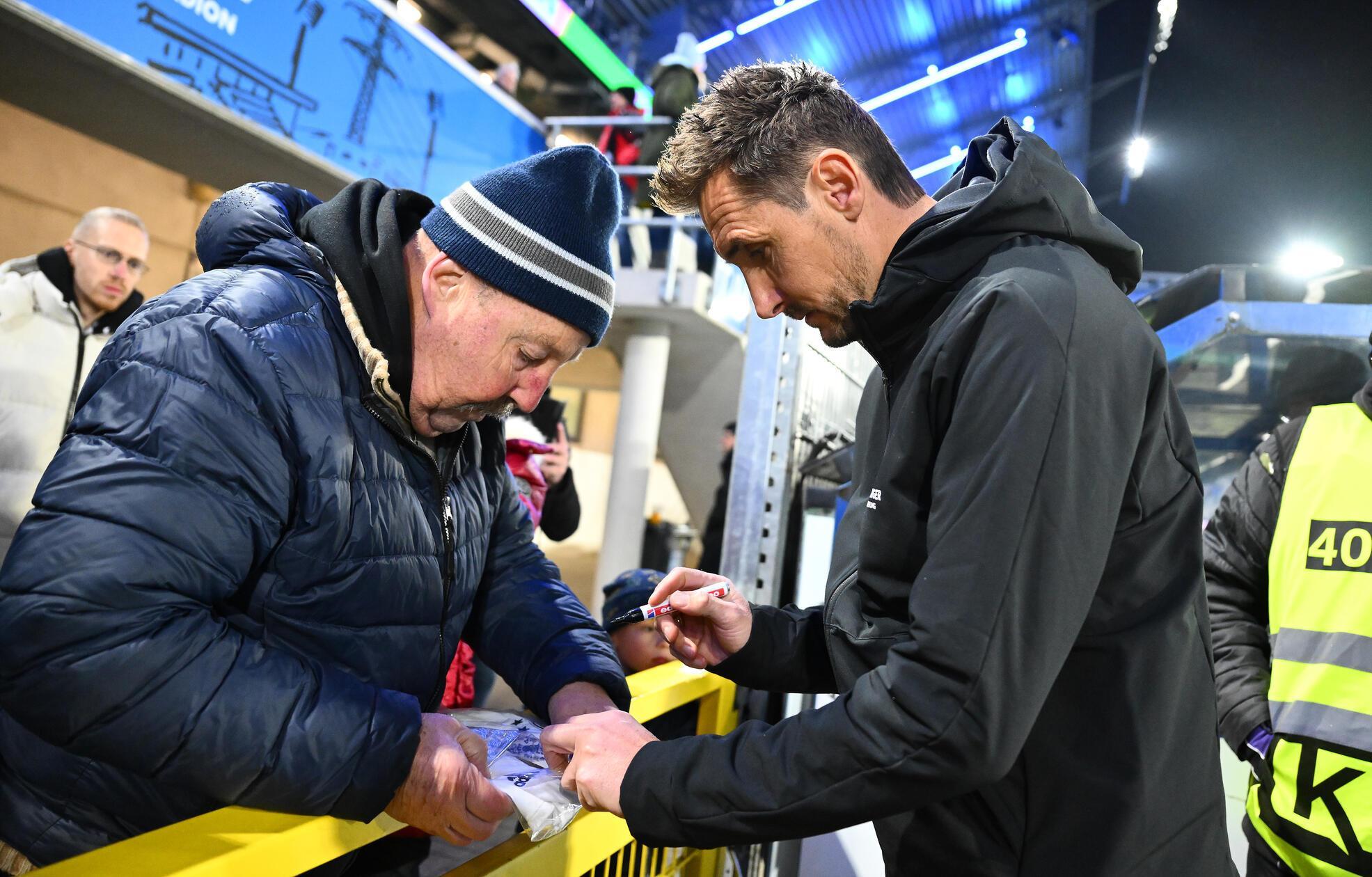Trainer Miroslav Klose verteilt vor Anpfiff noch Autogramme.