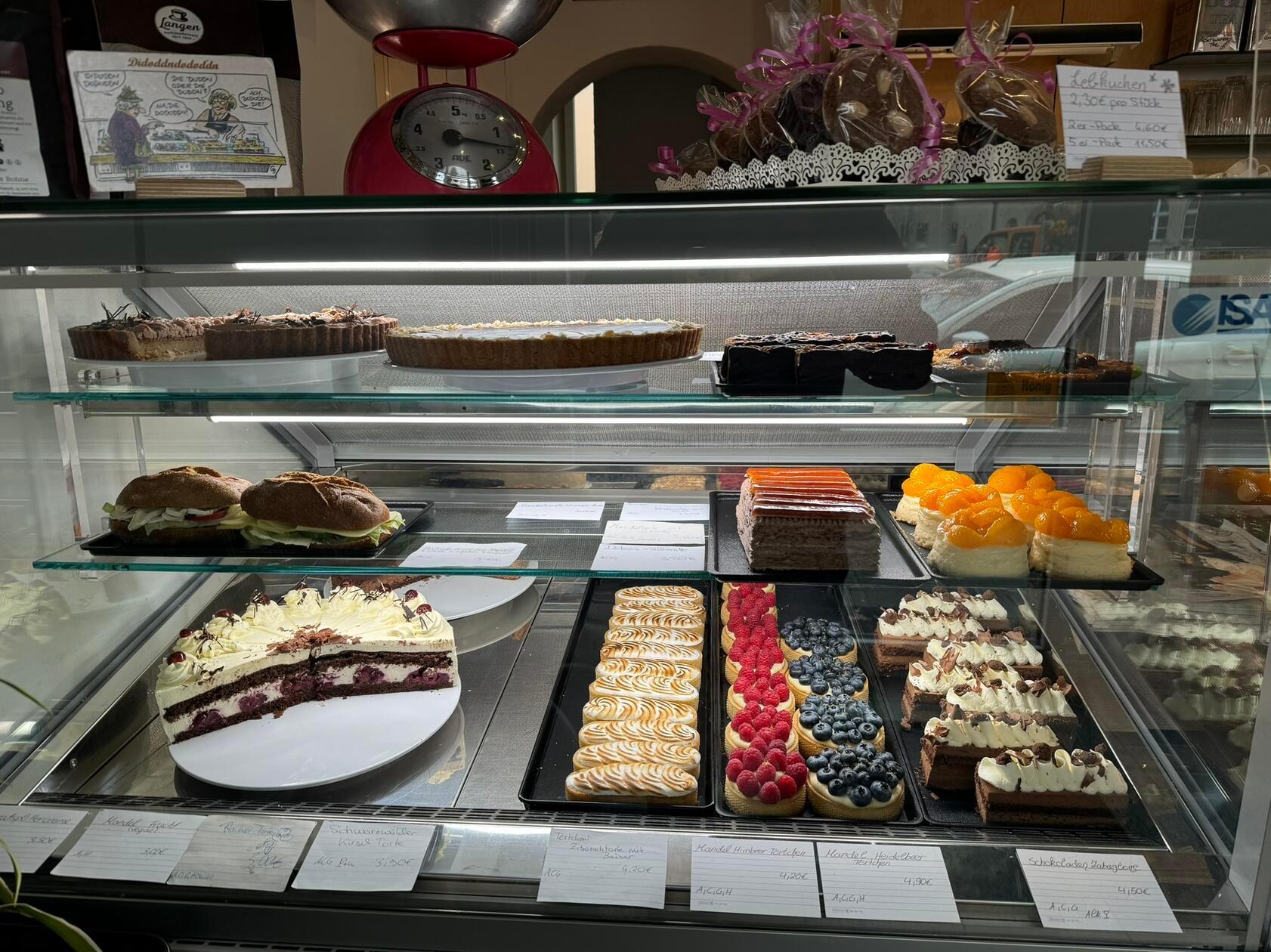 Die Kuchen, Schnitten und Torten wechseln täglich. Ab und zu schauen Kunden nur kurz herein, um zu evaluieren, ob sich ein Besuch diese Woche für sie lohnt, oder sie lieber auf die Auswahl der kommenden warten.