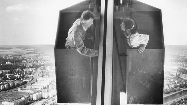TÜV-Gutachter inspizierten im Juli 1990 den Außenaufzug für Fensterputzer des damals im Nürnberger Fernmeldeturm beheimateten Restaurants. Der Ausblick der Besucher des in 189 Meter Höhe gelegenen Lokals war schon zwei Jahre lang getrübt gewesen. Der TÜV hatte verboten, die Scheiben zu putzen, nachdem der Außenaufzug 1988 bei einem Sturm beschädigt worden war. Ursprünglich sollte der gesamte Pylon abgeseilt und am Boden geprüft werden. Dieses teure Manöver ersparte TÜV-Ingenieur Günther Bäuerlein (li.) der Stadt: Er vertraute auf seine Schwindelfreiheit und reparierte den Aufzug deutlich kostengünstiger in luftiger Höhe.
