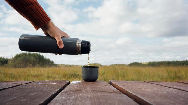 Man pouring tea from insulated bottle in cup model