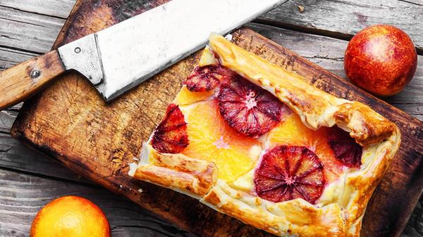 Cut piece of cheese cake with bright red oranges ,