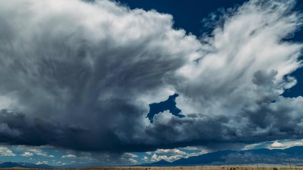 Large Storm cloud building over mountain range wit