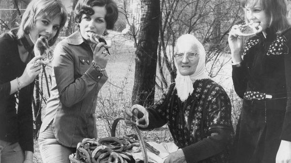 „Mädchen sind nicht mehr toupiert“ meldete die NN im März 1972 zu diesem Bild. Die Friseurinnung hatte die neuen Modefrisuren vorgestellt. Mädchen bis 19 Jahre sollten nun einen Schnitt erhalten, bei dem lästiges Sitzen unter der Trockenhaube wegfiel. Die Frisur mit kurzem Oberkopfhaar und langer Nackenpartie brauchte nur geföhnt zu werden. Sie ging unter dem Namen „Vokuhila“ (vorne kurz, hinten lang) in die Geschichte ein. Frauen bis 30 wurden große, natürliche Wellen empfohlen, wobei das Haar im Nacken eine füllige Innenrolle bildete. Von all dem völlig ungerührt trug die Brezenfrau im Stadtpark weiterhin ihr Kopftuch.