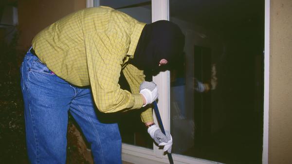 Ein maskierter Einbrecher bricht nachts mit einem
