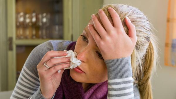 verschnupfte Frau putzt sich die Nase woman with a