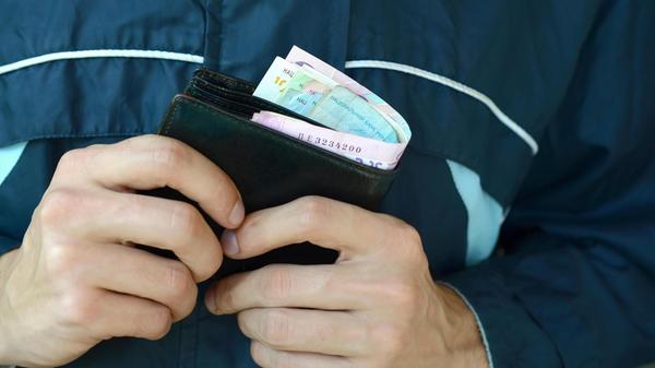 Man holds in hands black leather wallet with ukrai