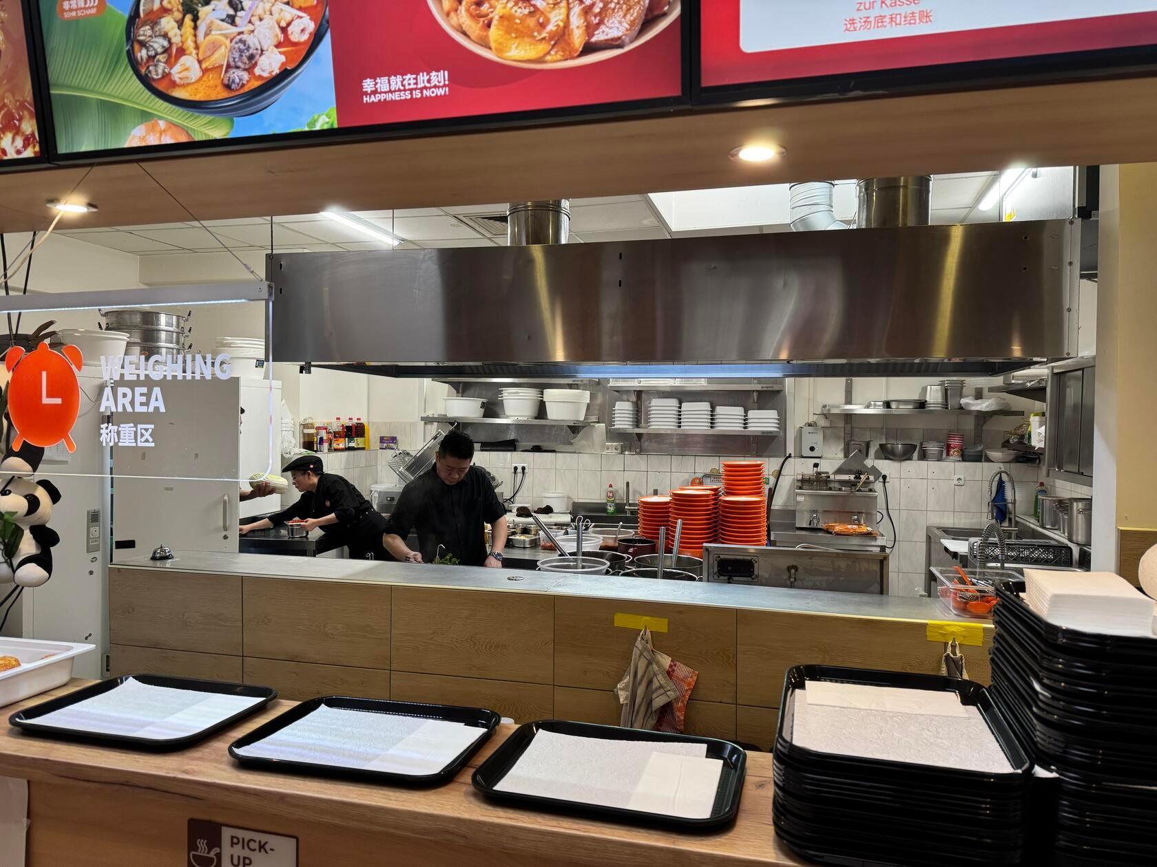 In der Küche stehen fleißige Köche an den Töpfen.