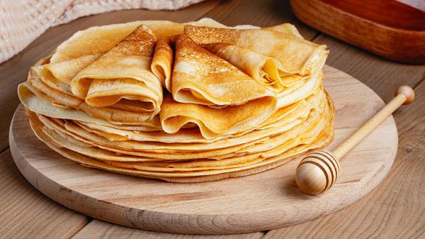 Thin pancakes on a wood plate. Homemade crepes, ta