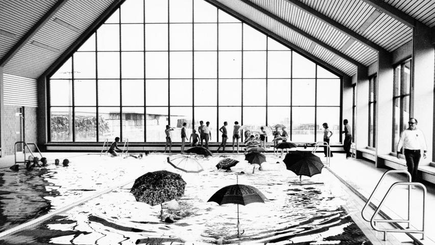 „I'm swimming in the rain!“ konnten Badegäste im Hallenbad in Stadeln aus gegebenem Anlass eine Weile lang singen, denn es regnete durch das Dach hinein. An dem erst im Jahr 1973 eröffneten Bad mussten bereits 1977 Renovierungsarbeiten durchgeführt werden. Auf unserem Archivbild sieht man nicht etwa die Schirmherren des Schwimmbades, sondern einige Badegäste, die bei den Feierlichkeiten zur Wiedereröffnung trockenen Humor bewiesen. „I'm swimming in the rain!“ konnten Badegäste im Hallenbad in Stadeln aus gegebenem Anlass eine Weile lang singen, denn es regnete durch das Dach hinein. An dem erst im Jahr 1973 eröffneten Bad mussten bereits 1977 Renovierungsarbeiten durchgeführt werden. Auf unserem Archivbild sieht man nicht etwa die Schirmherren des Schwimmbades, sondern einige Badegäste, die bei den Feierlichkeiten zur Wiedereröffnung trockenen Humor bewiesen.