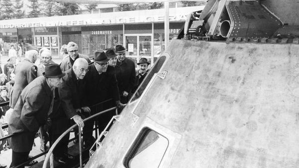„Apollo 10 im Quelle-Markt gelandet“, hieß es im November 1970 in einer Anzeige in den NN. Die Kommandokapsel des Raumschiffes, das zur Generalprobe einer Mondlandung unterwegs gewesen war, wurde für ein paar Tage auf dem Quelle-Parkplatz in Nürnberg ausgestellt. Viele kamen, um das Gefährt zu sehen, mit dem drei Astronauten im Mai 1969 den Mond 31 mal umkreist und das Gebiet inspiziert hatten, in dem zwei Monate später Apollo 11 landen sollte. Auch Gustav Schickedanz (2. von li.) und Oberstaatsanwalt Hans Sachs (hinten re.) bestaunten die Kapsel, an der Beulen und verkohlte Stellen von der gefahrvollen Reise zeugten.