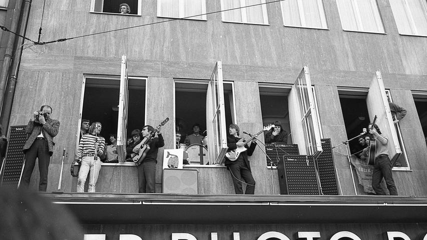 Eine äußerst ungewöhnliche Konzertbühne hatte sich am 23.02.1966 die Beat-Band „Jonah and the Whales“ (aus der später die Band „Ihre Kinder“ hervorgehen sollte) in der Nürnberger Altsstadt gesucht. Die Band kletterte durch die Fenster auf das ungesicherte Vordach des Geschäftes Photo Porst in der Karolinenstrasse 3 und legte los, sehr zur Begeisterung des, bedingt durch die Karnevalszeit, reichlich auf der Straße vorhandenen Publikums. Auch ein Fotograf traute sich damals mit auf das Dach, neben ihm sieht man von links Sonny Hennig, Wuffel Stumm, Roland Multhaupt am Schlagzeug im Fenster, Günter Gast und Ernst Schultz. Der damalige Band-Manager Jonas Porst hat es leider nicht auf unser Bild geschafft. Eine äußerst ungewöhnliche Konzertbühne hatte sich am 23.02.1966 die Beat-Band „Jonah and the Whales“ (aus der später die Band „Ihre Kinder“ hervorgehen sollte) in der Nürnberger Altsstadt gesucht. Die Band kletterte durch die Fenster auf das ungesicherte Vordach des Geschäftes Photo Porst in der Karolinenstrasse 3 und legte los, sehr zur Begeisterung des, bedingt durch die Karnevalszeit, reichlich auf der Straße vorhandenen Publikums. Auch ein Fotograf traute sich damals mit auf das Dach, neben ihm sieht man von links Sonny Hennig, Wuffel Stumm, Roland Multhaupt am Schlagzeug im Fenster, Günter Gast und Ernst Schultz. Der damalige Band-Manager Jonas Porst hat es leider nicht auf unser Bild geschafft.