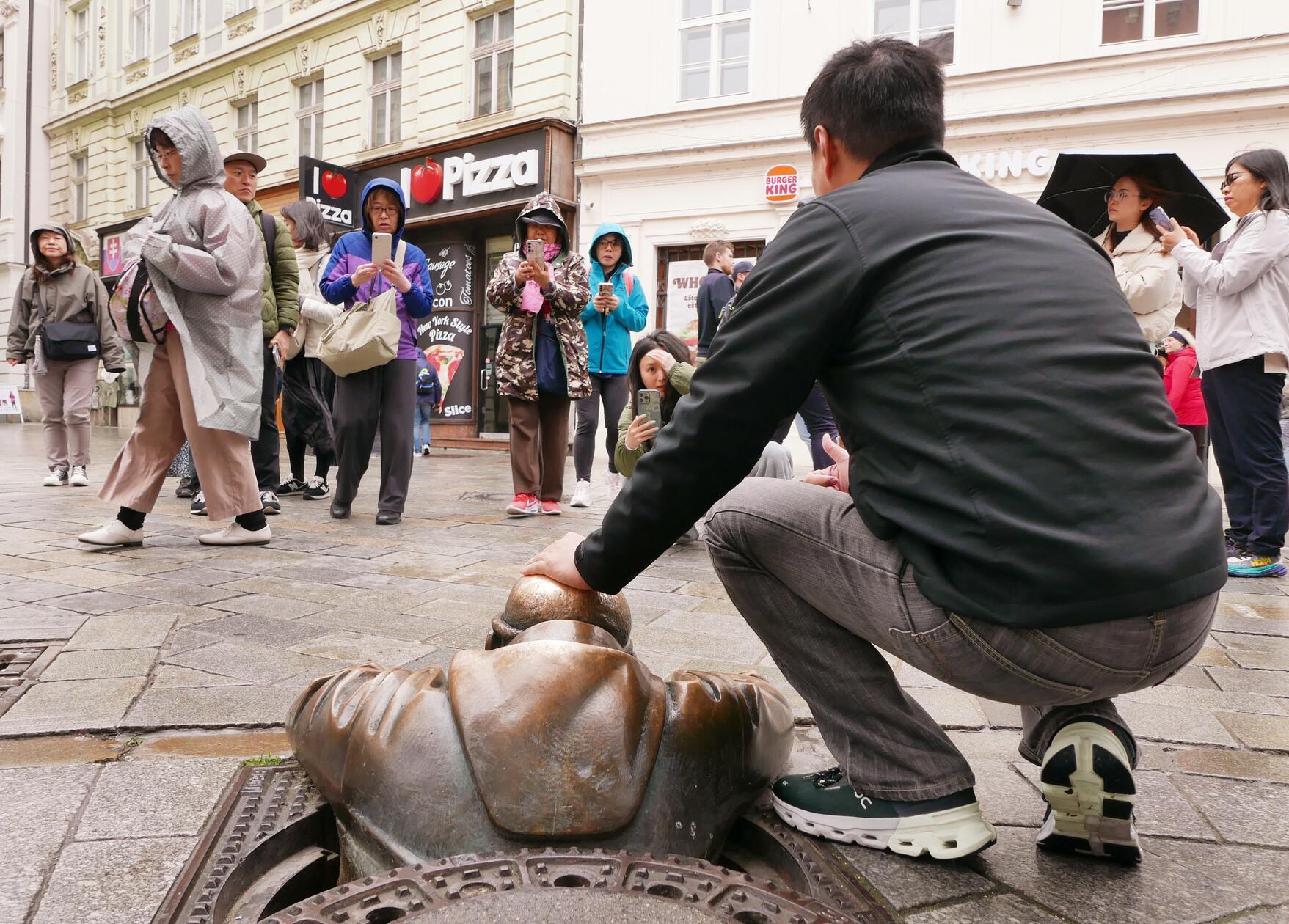 Alle Touristen wollen unbedingt diese Skulptur streicheln, die ihren Kopf aus dem Gully steckt.