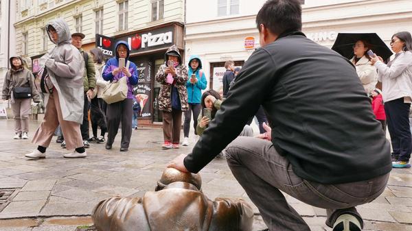 Alle Touristen wollen unbedingt diese Skulptur streicheln, die ihren Kopf aus dem Gully steckt.