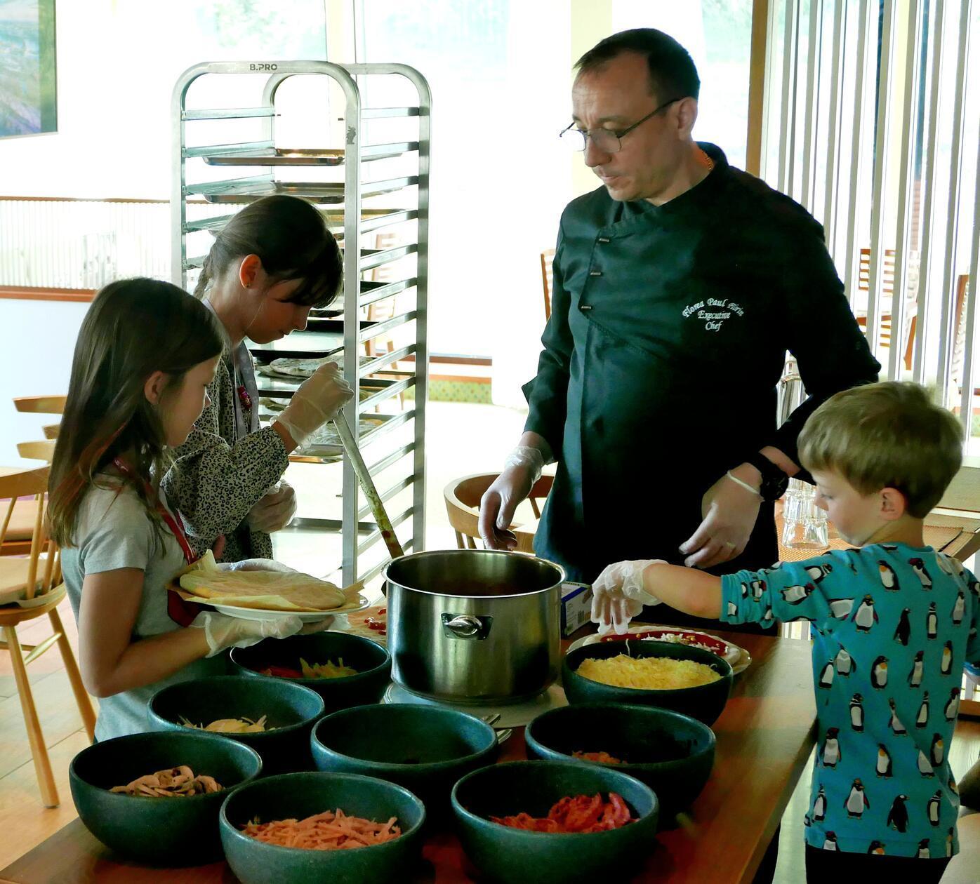 Im Restaurant macht der Chefkoch mit den Kindern Pizza.